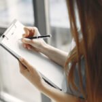 En kvinna bockar av på en checklista som hjälper inför att sälja sin bil.