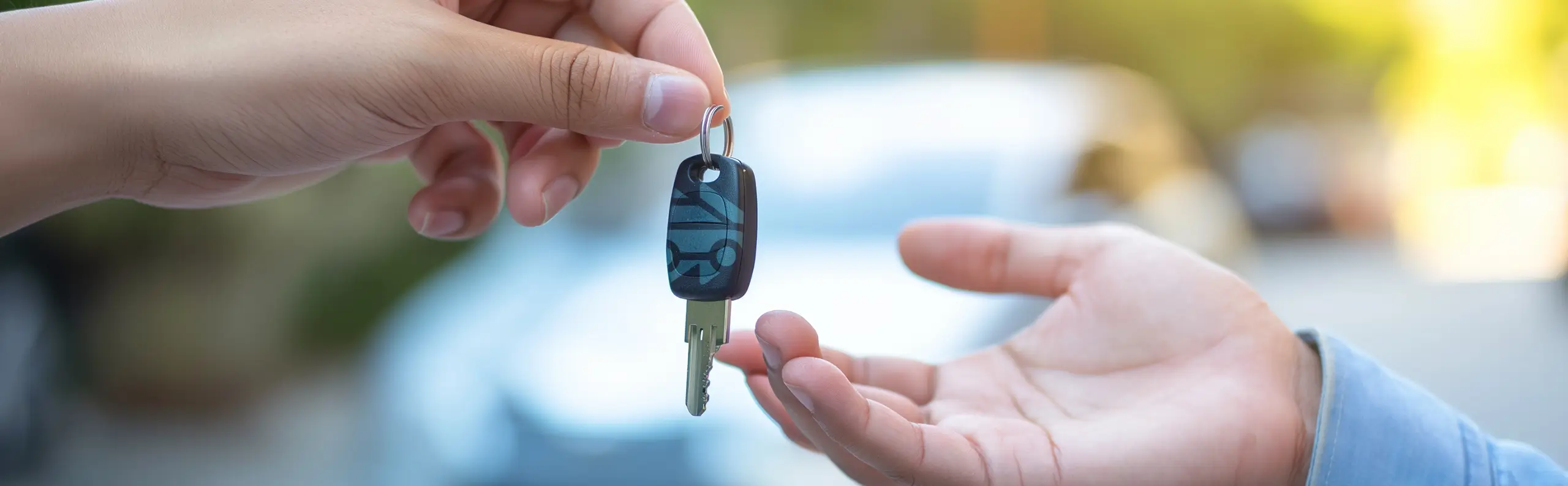 Redo att Sälja bilen snabbt och lämna över bil nycklarna? Två händer som möts och bilnycklar som lämnas över en solig dag i Sverige.